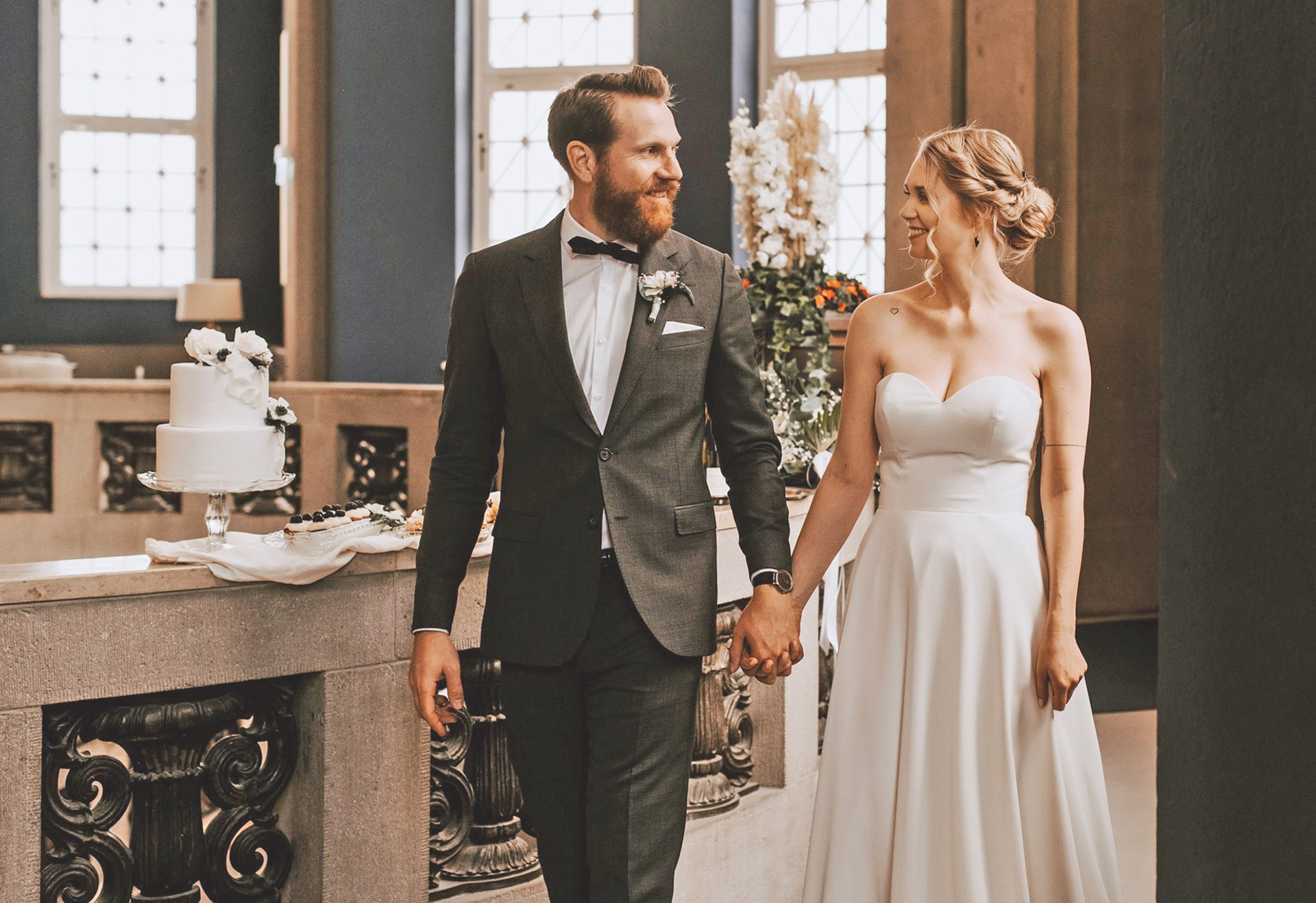 Brautpaar Hand in Hand, im Hintergrund die Hochzeitstorte
