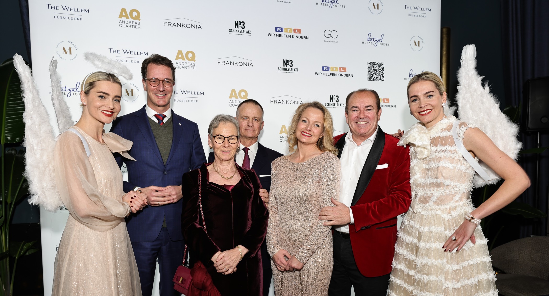Gäste und zwei Frauen in Engelskostümen vor der Fotowand beim CCCC-Event für RTL – Wir helfen Kindern