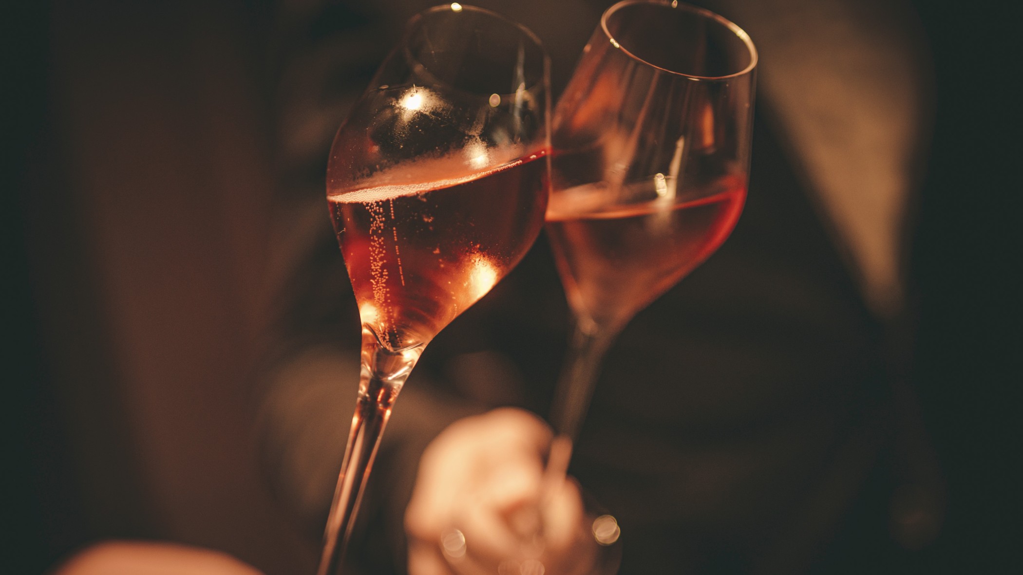 Anstoßen mit zwei Gläsern Rosé-Schaumwein in der gedämpften Atmosphäre des FRANK'S Club