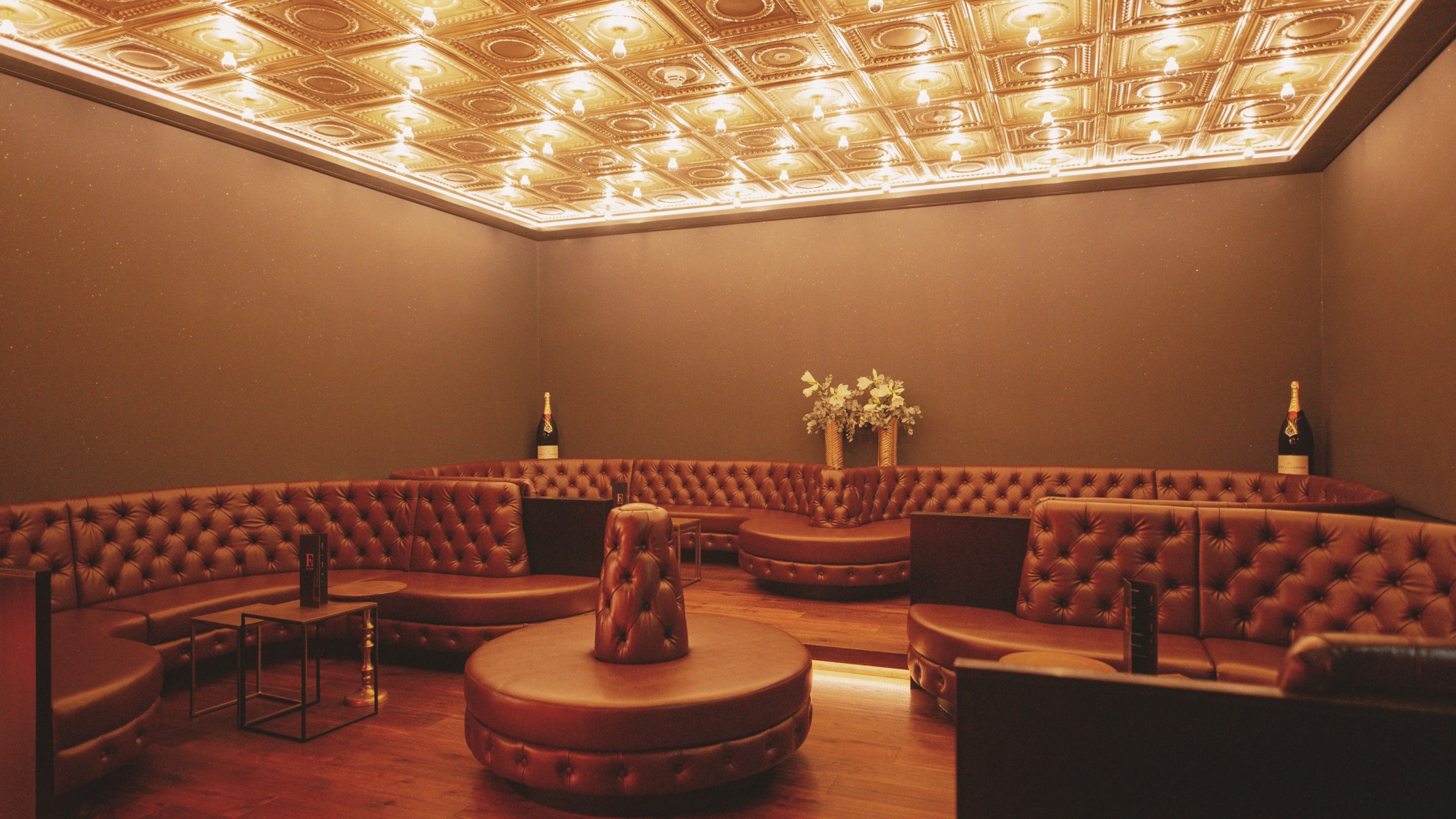 Lounge mit gesteppten Leder-Sitzbänken und beleuchteter Kassettendecke im FRANK'S Club