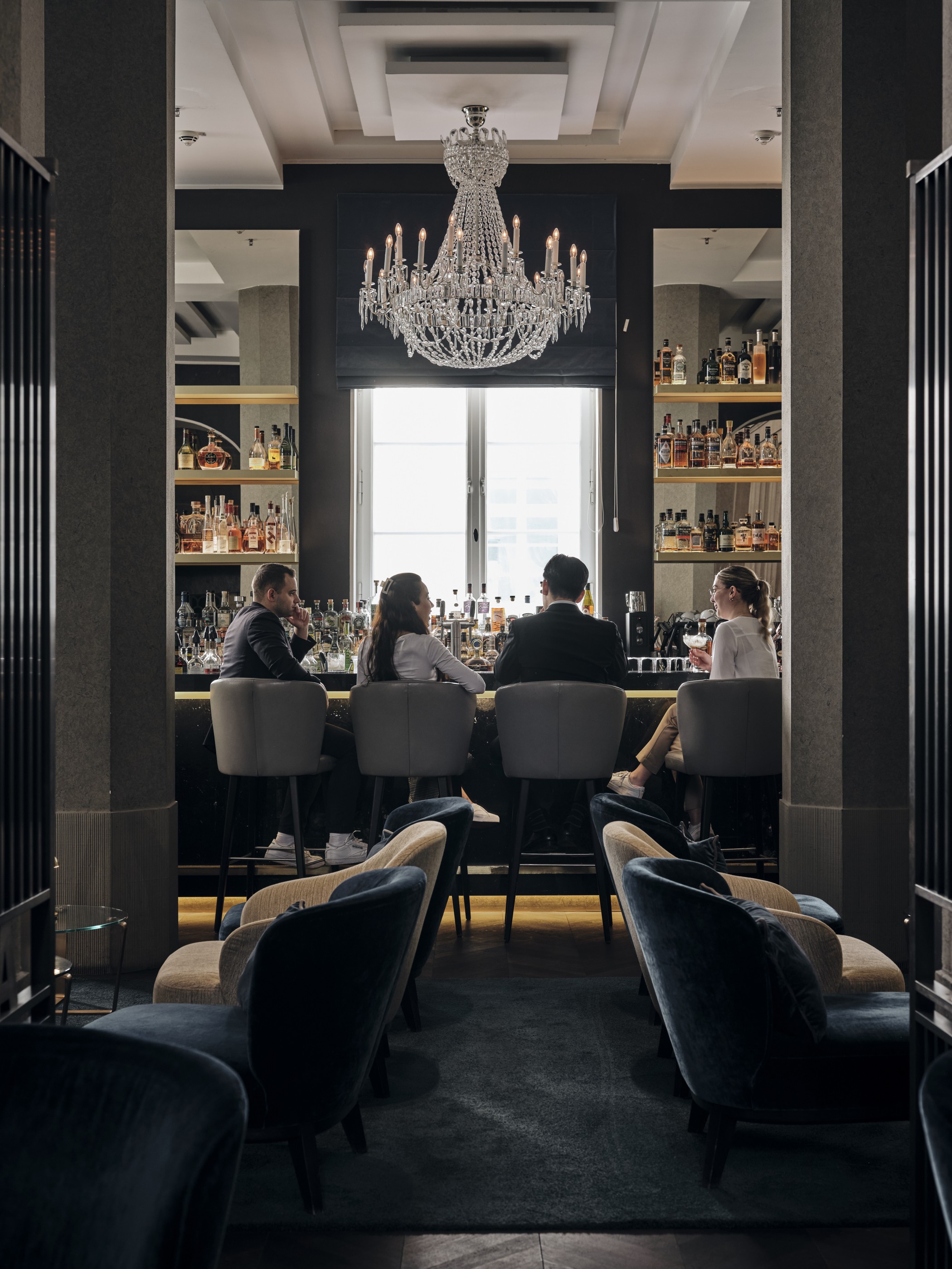 THE WELLEM Bar mit Kronleuchter und Gästen an der Bar im The Wellem Hotel im Andreas Quartier in Düsseldorf