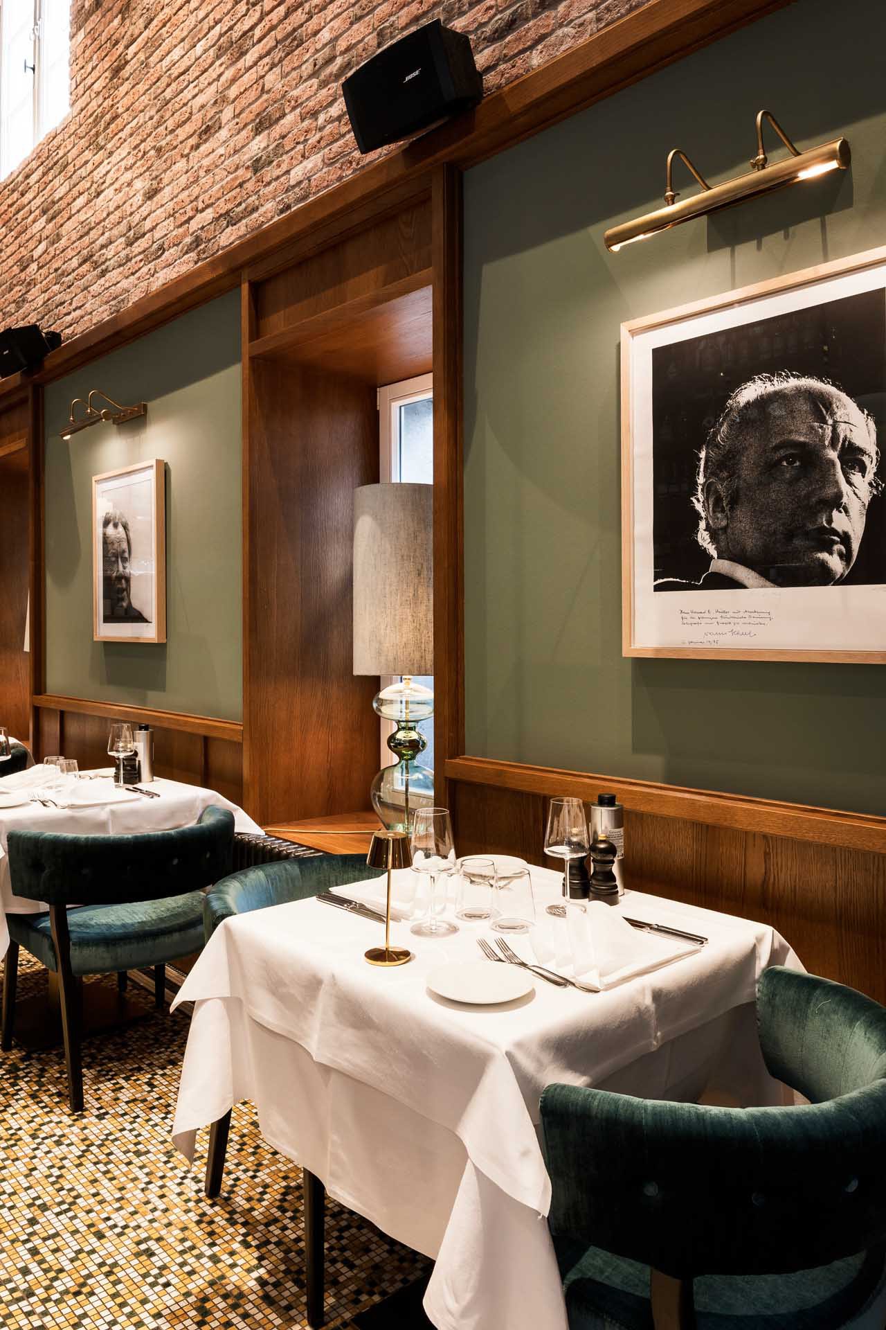 Laid table at il punto in front of green wood panelling with a black-and-white portrait