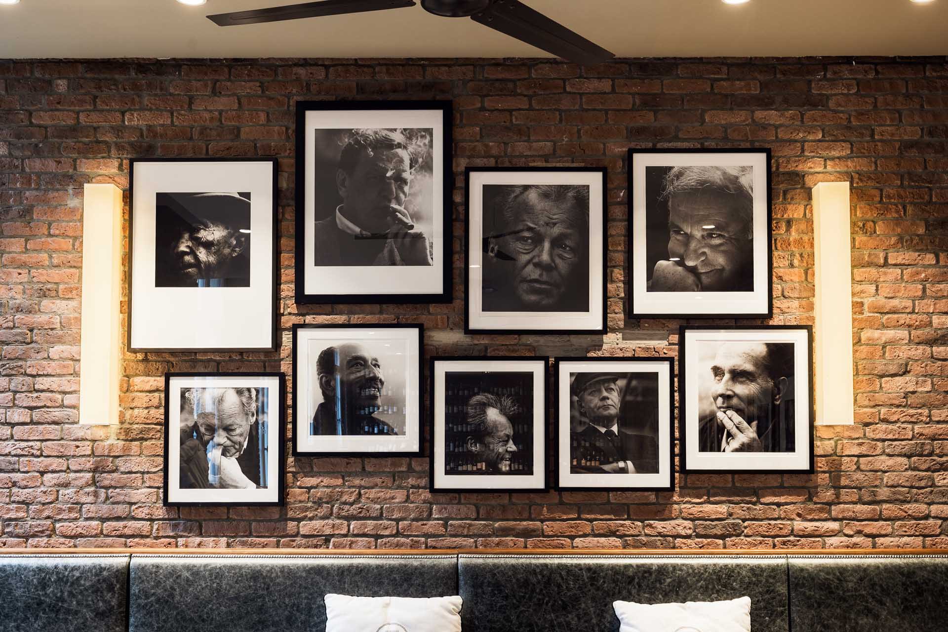 Brick wall at il punto with framed black-and-white portraits above a banquette