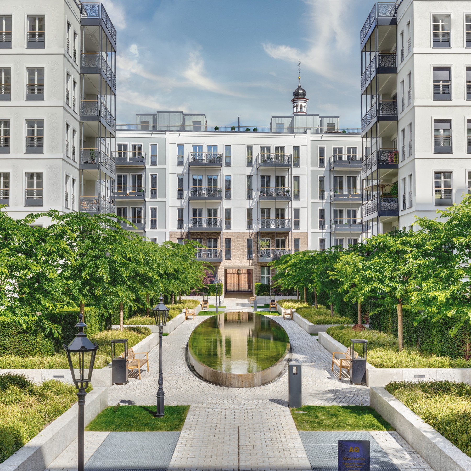 Andreas Garten mit Wasserbecken, Laternen und Baumreihen zwischen hellen Wohngebäuden des Andreas Quartiers