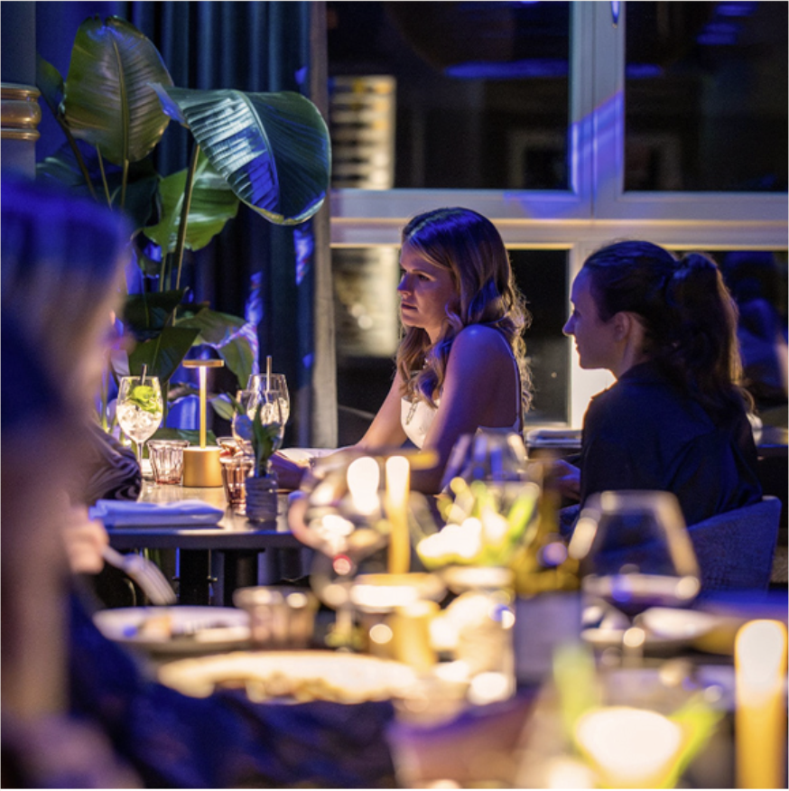 Gäste beim Abendessen bei Kerzenlicht im blau beleuchteten FRANK'S Restaurant