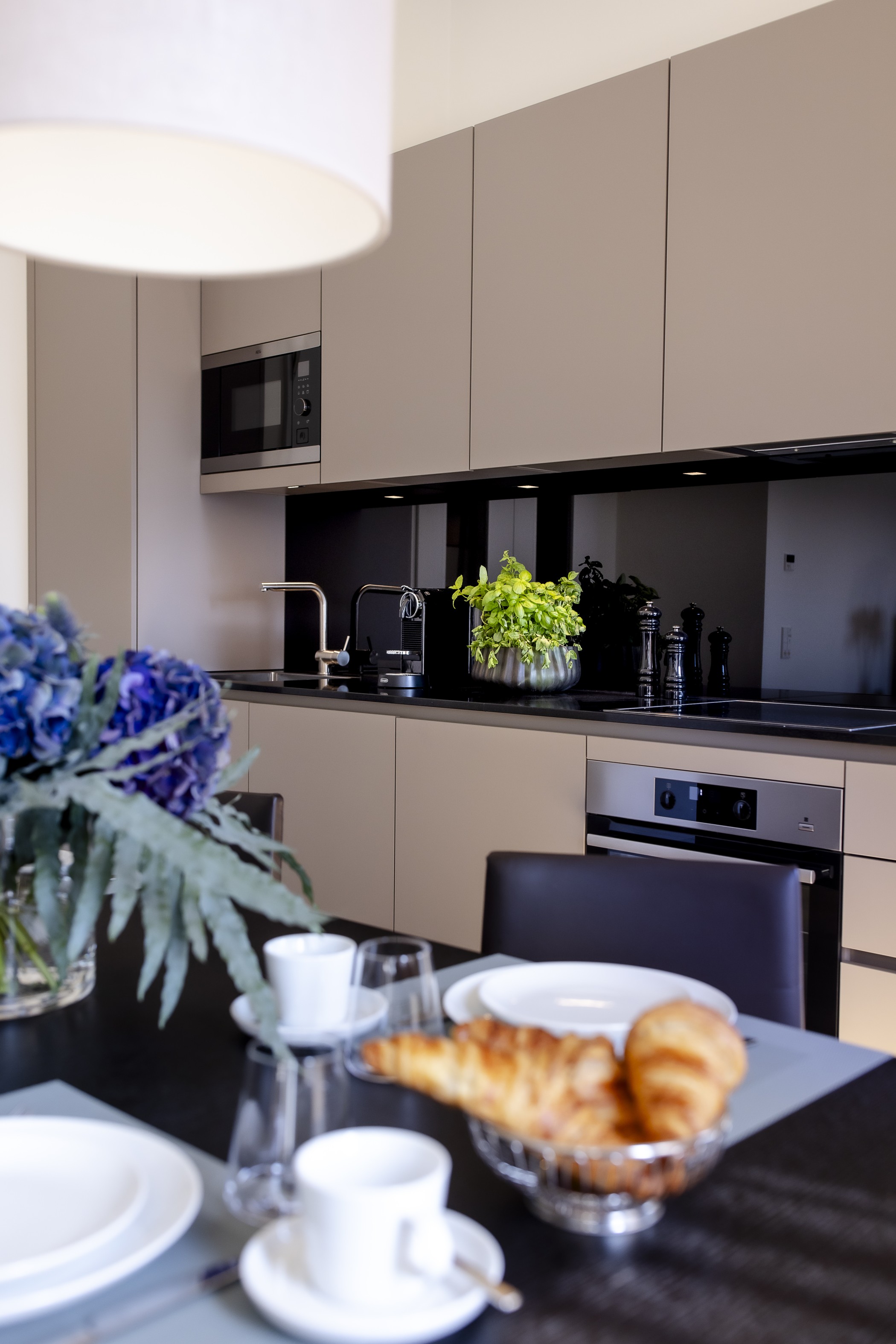 Küche einer Residence mit gedecktem Frühstückstisch, Croissants und Kaffeetassen