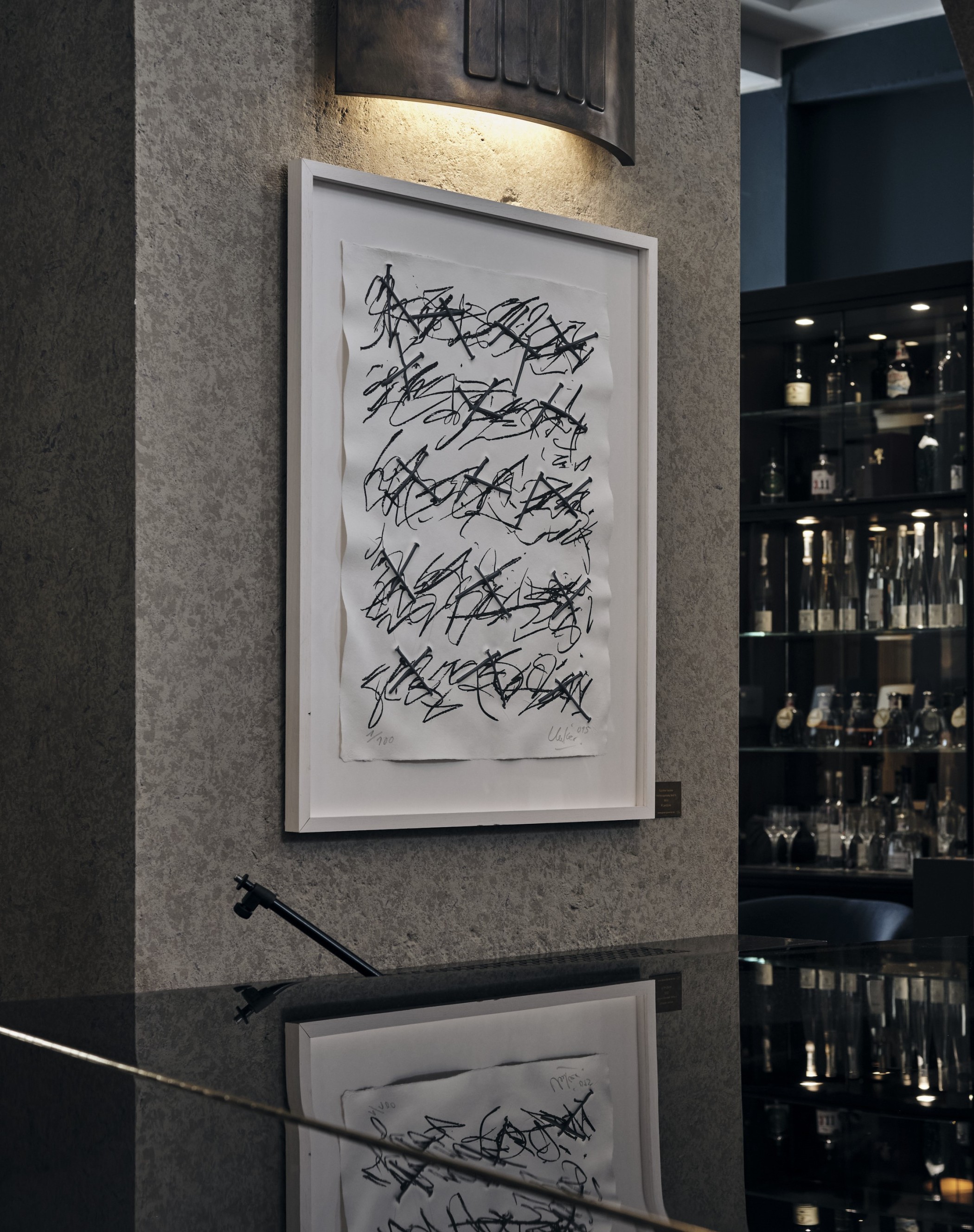 Kunstwerk von Günther Uecker an einer Steinwand in der THE WELLEM Bar
