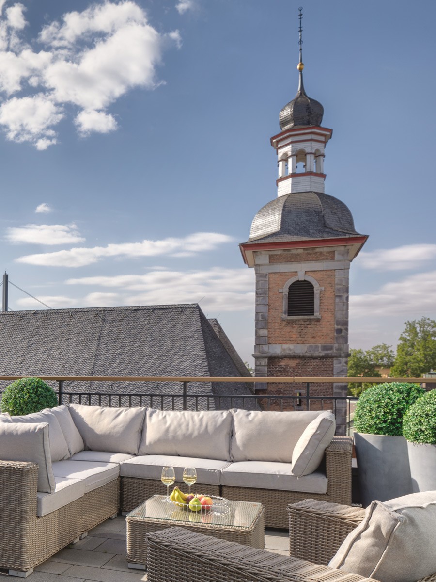 Dachterrasse mit Rattan-Lounge und Blick auf den Turm der Andreaskirche