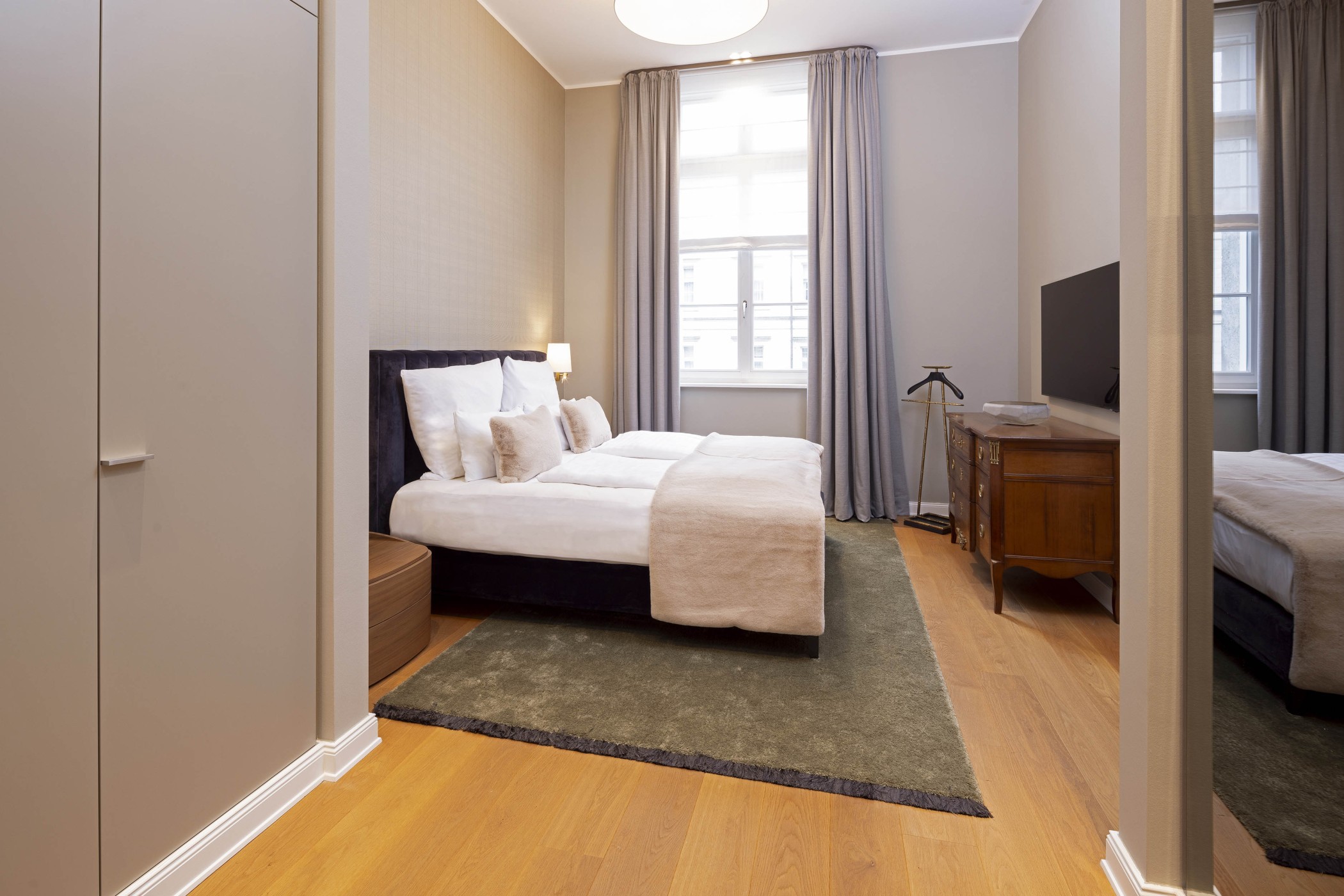 Schlafzimmer mit Doppelbett, antiker Kommode und hohem Fenster