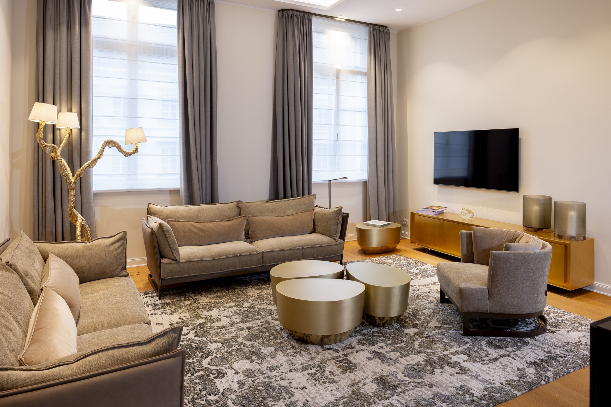 Wohnbereich einer Präsidentensuite mit Sofas, goldenen Couchtischen und Stehleuchte in Astform