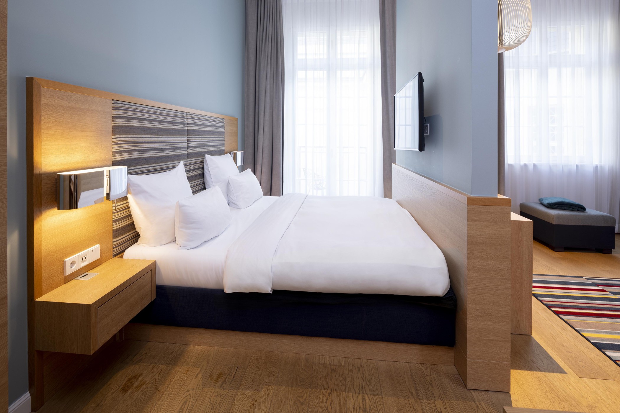 Sleeping area of a suite at The Wellem with double bed and half-height wooden partition