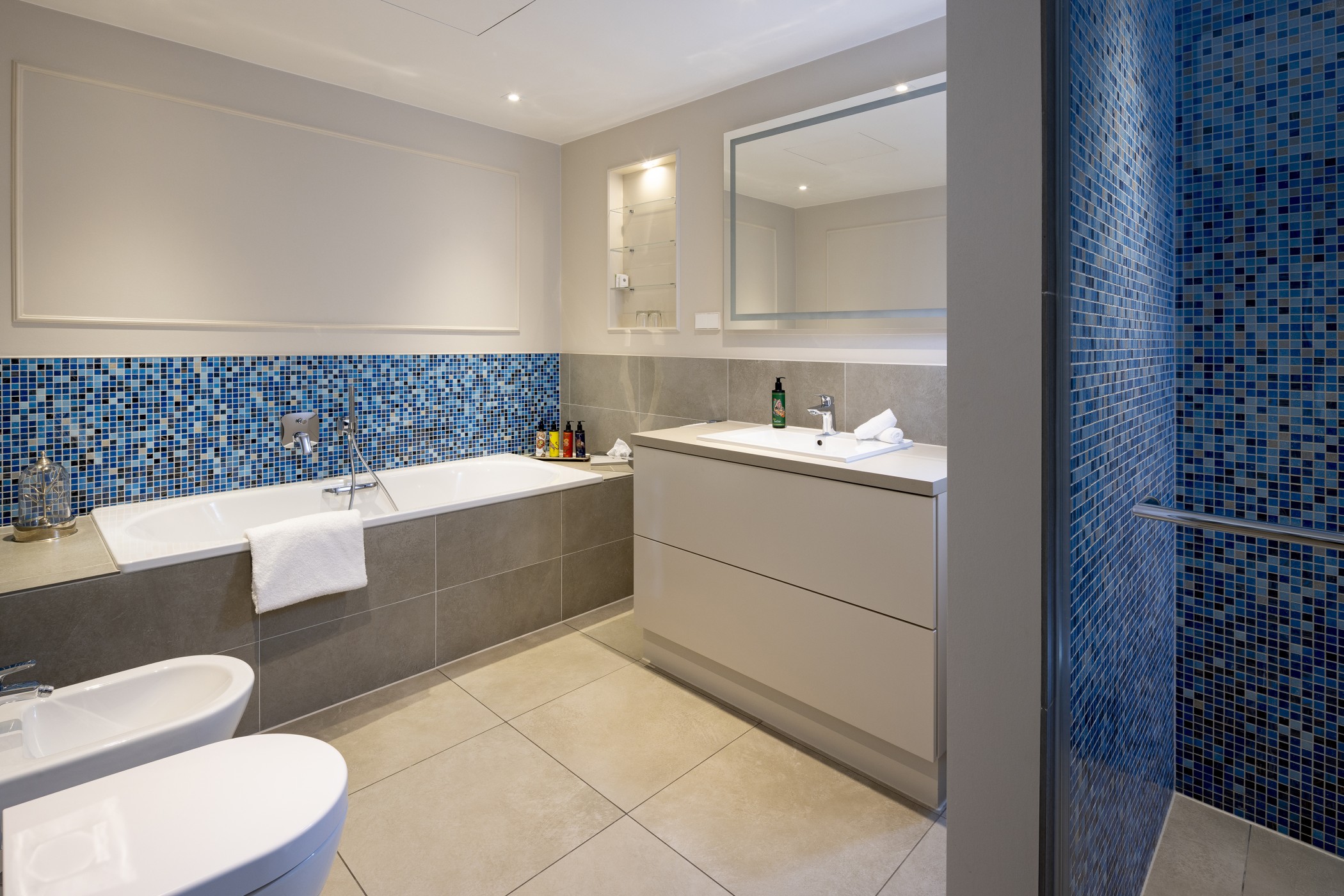 Suite bathroom with bathtub, blue mosaic tiles and vanity unit