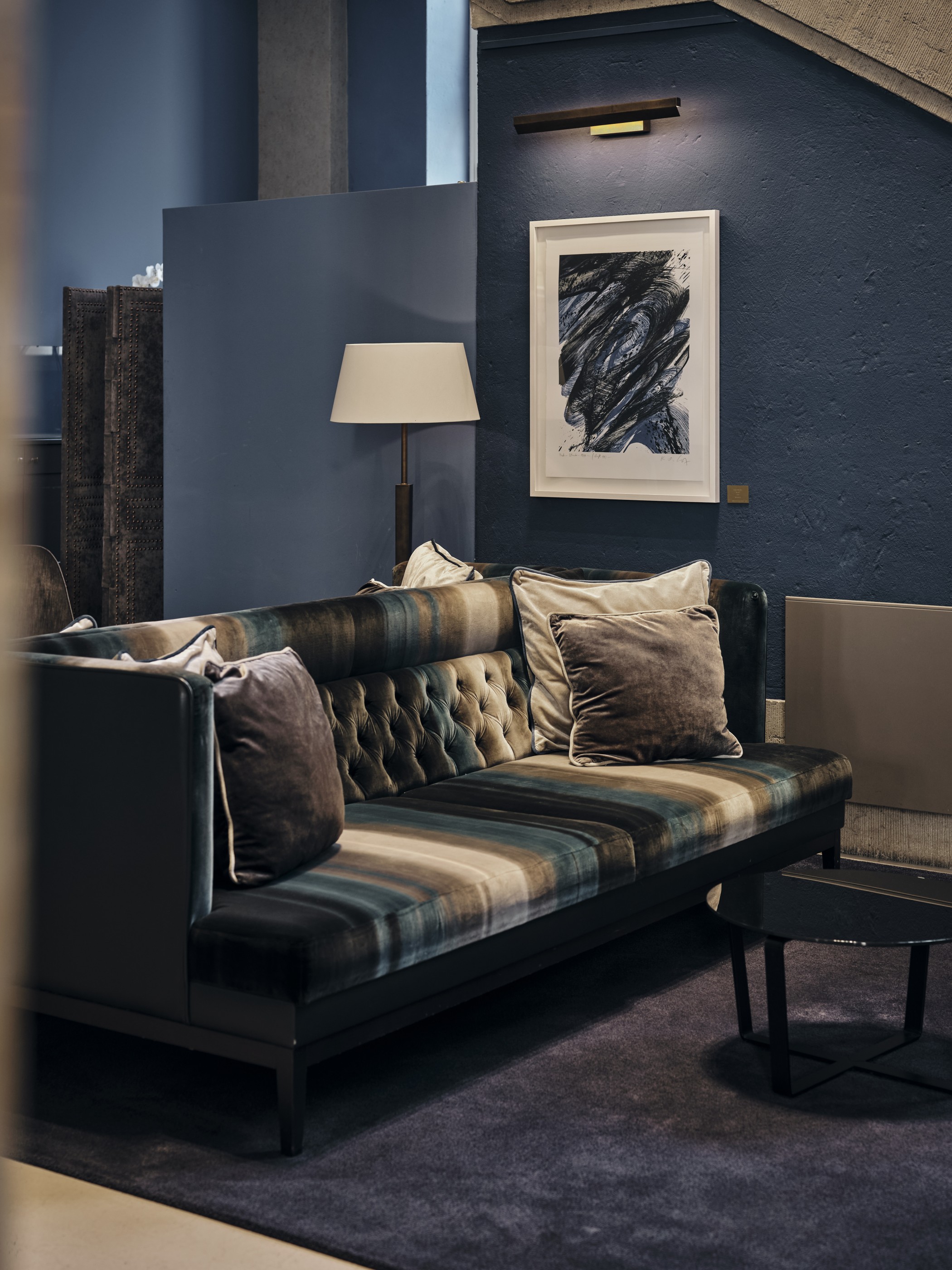 Loge auf der Empore mit gesteppter Polsterbank, Kissen, Stehlampe und abstraktem Kunstwerk an blauer Wand